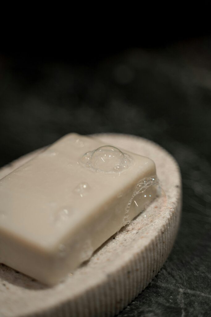pexels-photo-9145344-9145344 Close-up of a soap bar with bubbles on a stone holder, emphasizing cleanliness and spa aesthetics.